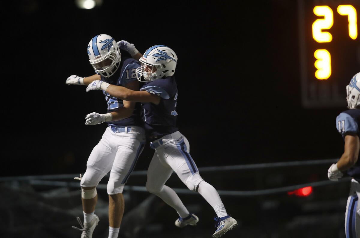 Corona del Mar's Simon Hall, left, celebrates his touchdown with teammate Riley Binnquist against Downey in the first half of a season opener at Newport Harbor High on Aug. 23.