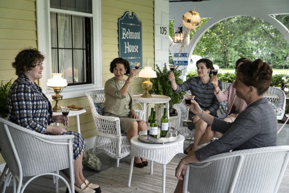 A group of women in the 1950s toast on the porch of an inn
