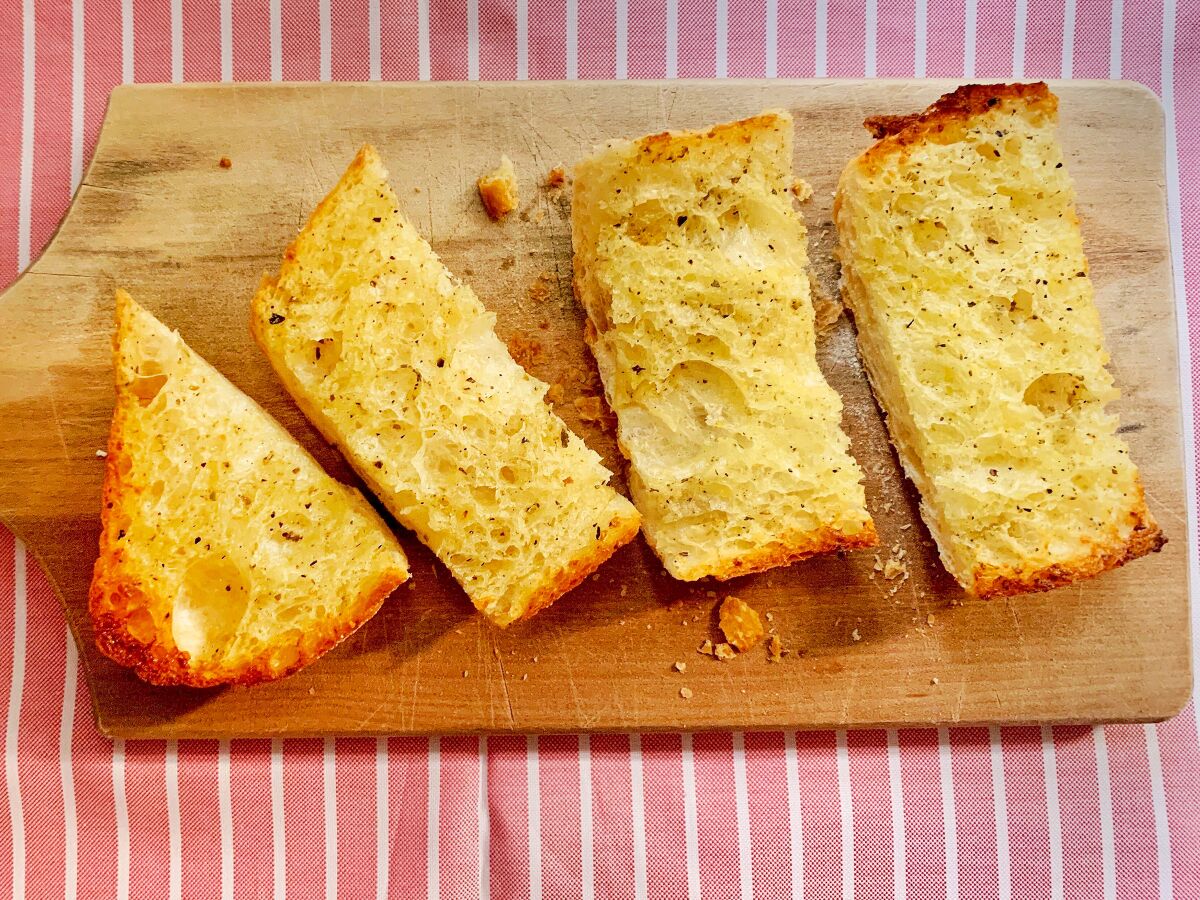 Four slices of garlic bread on a wooden cutting board
