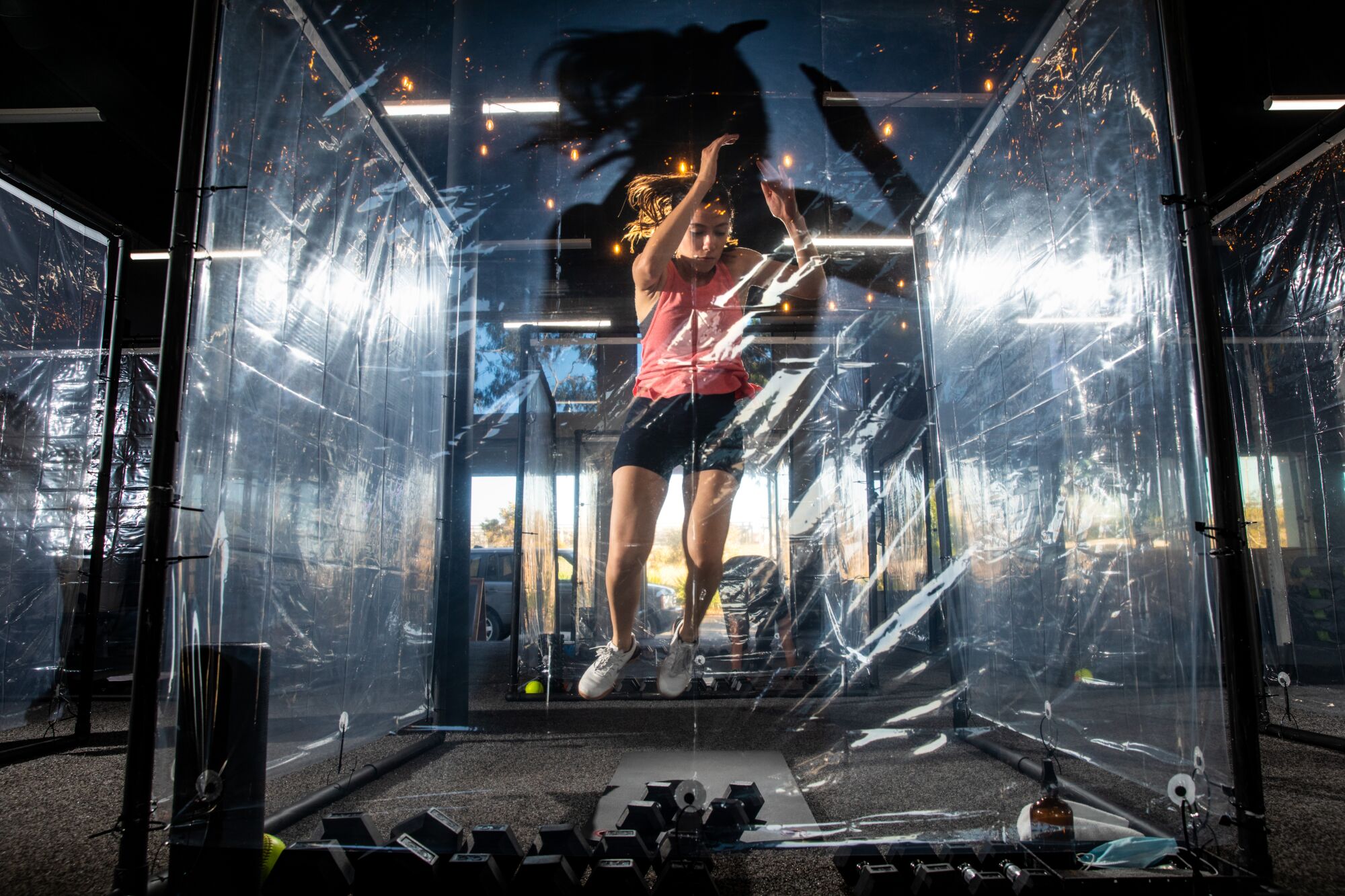A woman jumps while exercising inside a transparent plastic pod in a gym