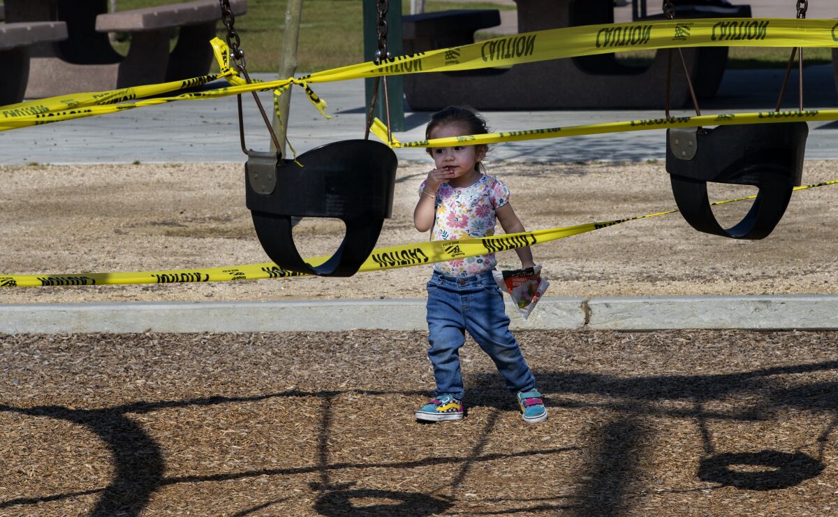 Adeline Hernandez approaches swing sets at Ryan Bonaminio Park in Riverside that are closed in April.