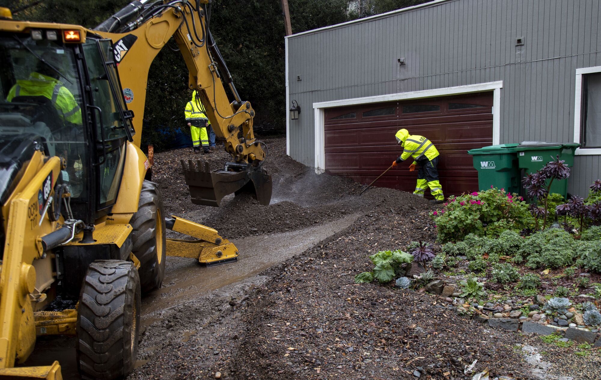 Work crew clears mud from a driveway in Silverado Canyon.