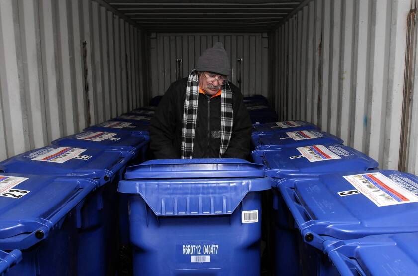 Volunteer Michael Lindley rolls a bin back into the Check-in Storage trailer at Venice Beach. The pilot program lets people retrieve their items between 3 and 5 p.m. daily.