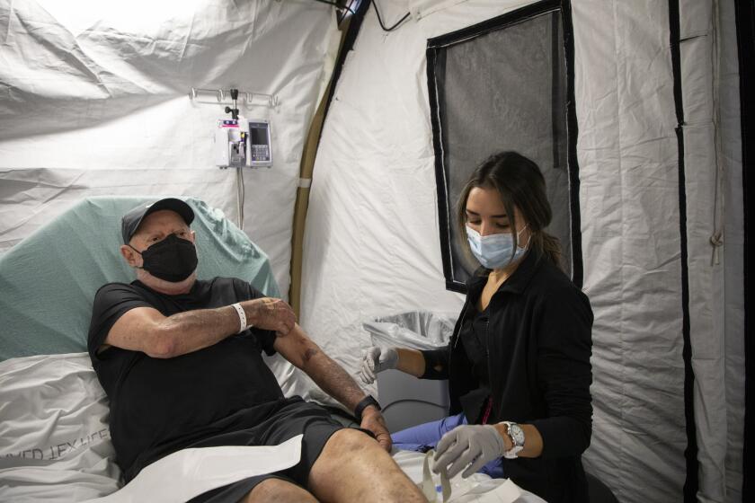 Encinitas, CA - November 11: Mark Swenson, 71, of Oceanside, left, has his blood drawn by Jessica Smith, a registered nurse, after having low sodium at Scripps Memorial Hospital Encinitas on Friday, Nov. 11, 2022 in Encinitas, CA. Scripps recently opened an overflow tent outside of the hospital after an increase of flu patients. (Ana Ramirez / The San Diego Union-Tribune)