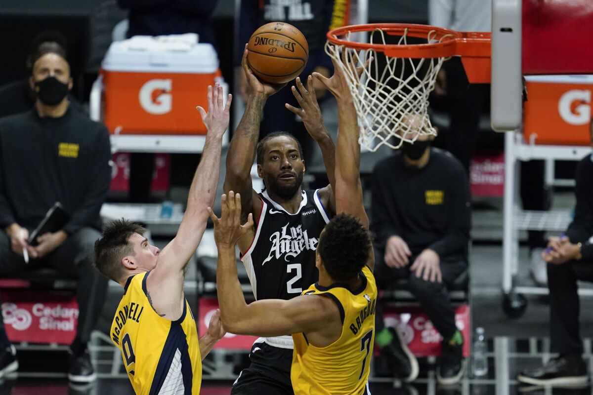 Clippers forward Kawhi Leonard shoots over Indiana Pacers guards T.J. McConnell and Malcolm Brogdon.
