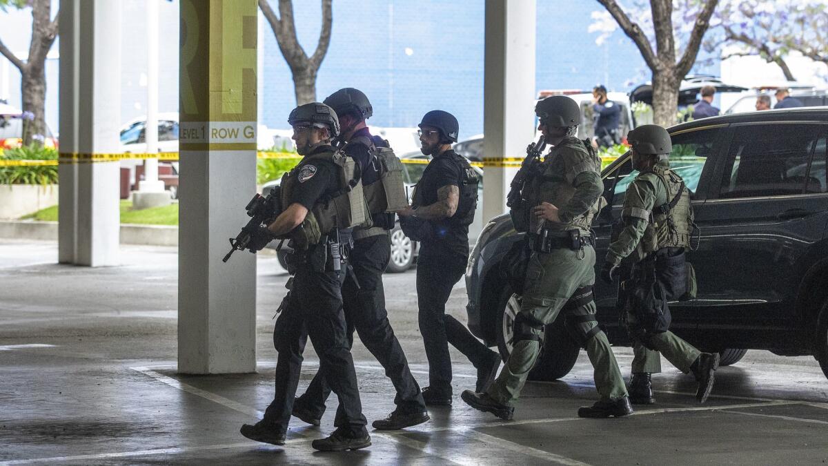 Police walk through a parking structure while preparing to enter the Del Amo Fashion Center in Torrance after a shooting that injured one man.