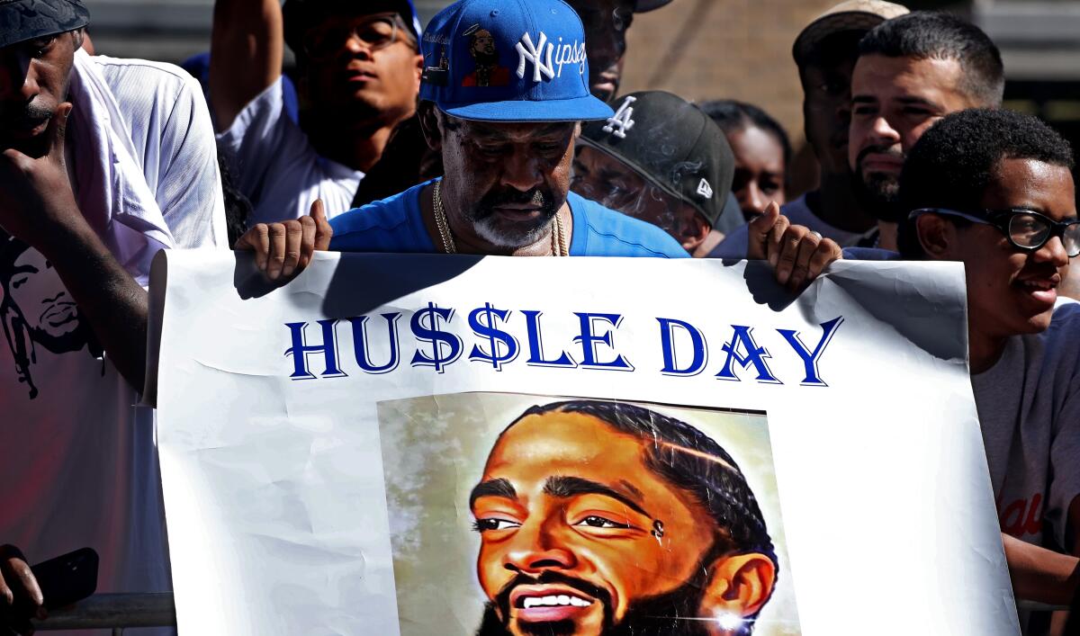 A man holds up a sign honoring Nipsey Hussle at Monday's Walk of Fame ceremony for the late rapper.