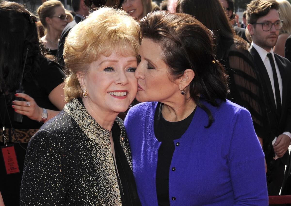 Carrie Fisher kisses her mother, Debbie Reynolds, as they arrive at the Primetime Creative Arts Emmy Awards in Los Angeles in 2011.