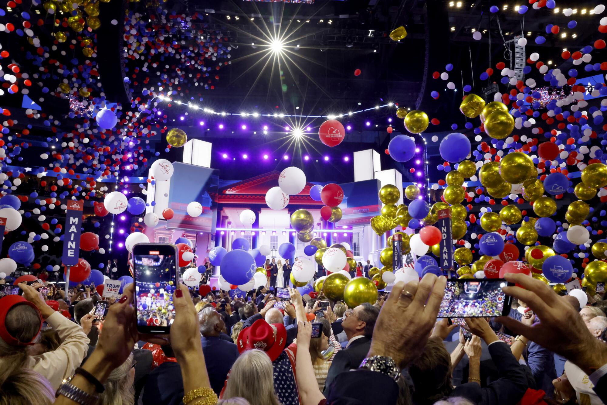 Delegates takes pictures of Republican candidate former President Donald Trump and his wife on stage as balloons drop