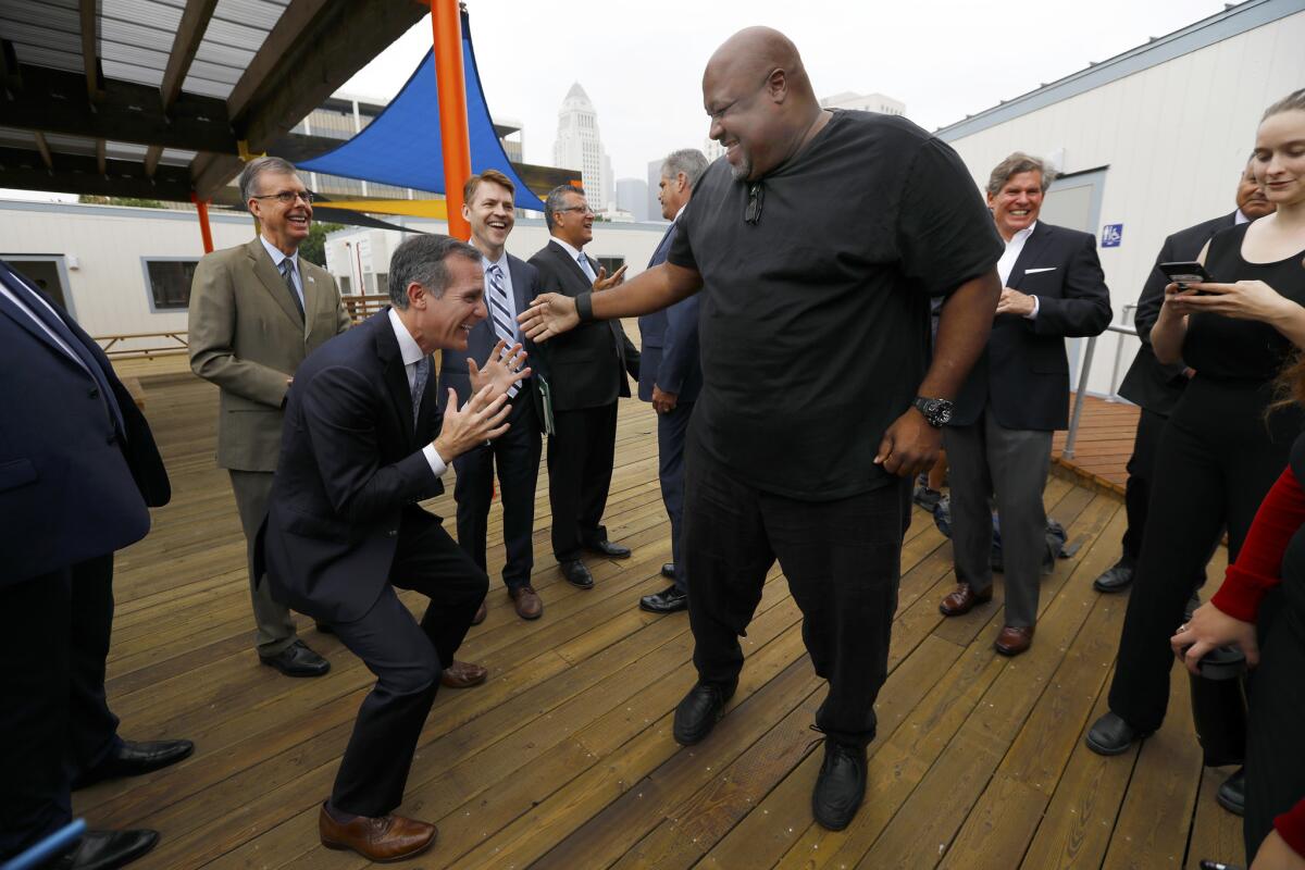 L.A. Mayor Eric Garcetti, left, reacts after Big Joe, right, lifted him up following a news conference Wednesday at the new temporary homeless shelter in downtown.