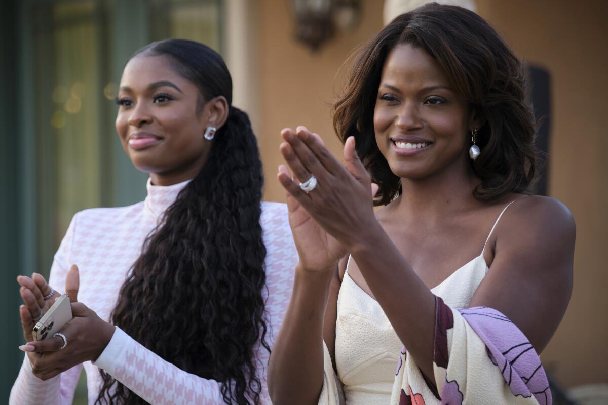 Two elegantly dressed women applaud.