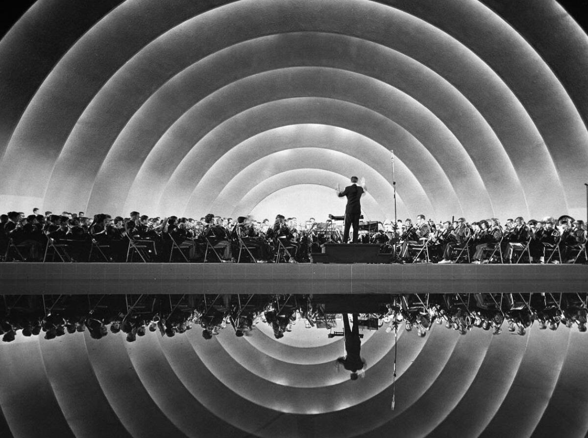 A conductor leads an orchestra at the Hollywood Bowl, in a black-and-white photo from the audience view.