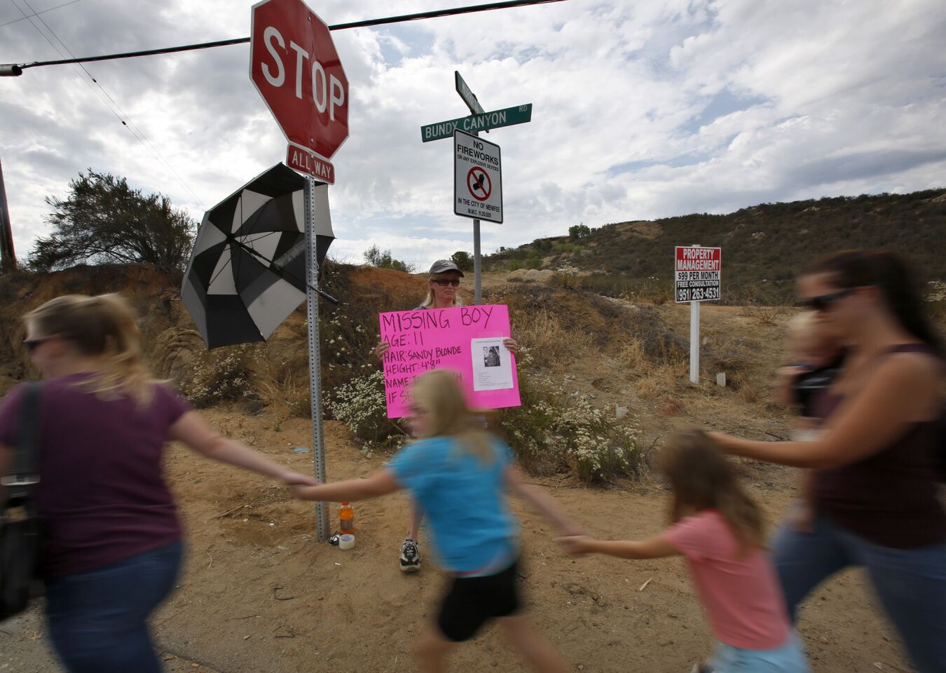 Debi Velivis holds a sign at the intersection of Bundy Canyon Road and Murrieta Road with information about missing 11-year-old Terry Dewayne Smith.