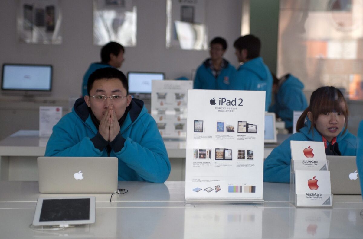 An Apple store employees wait for customers near MacBook laptops and iPads in the city of Qingdao in eastern China's Shandong province.