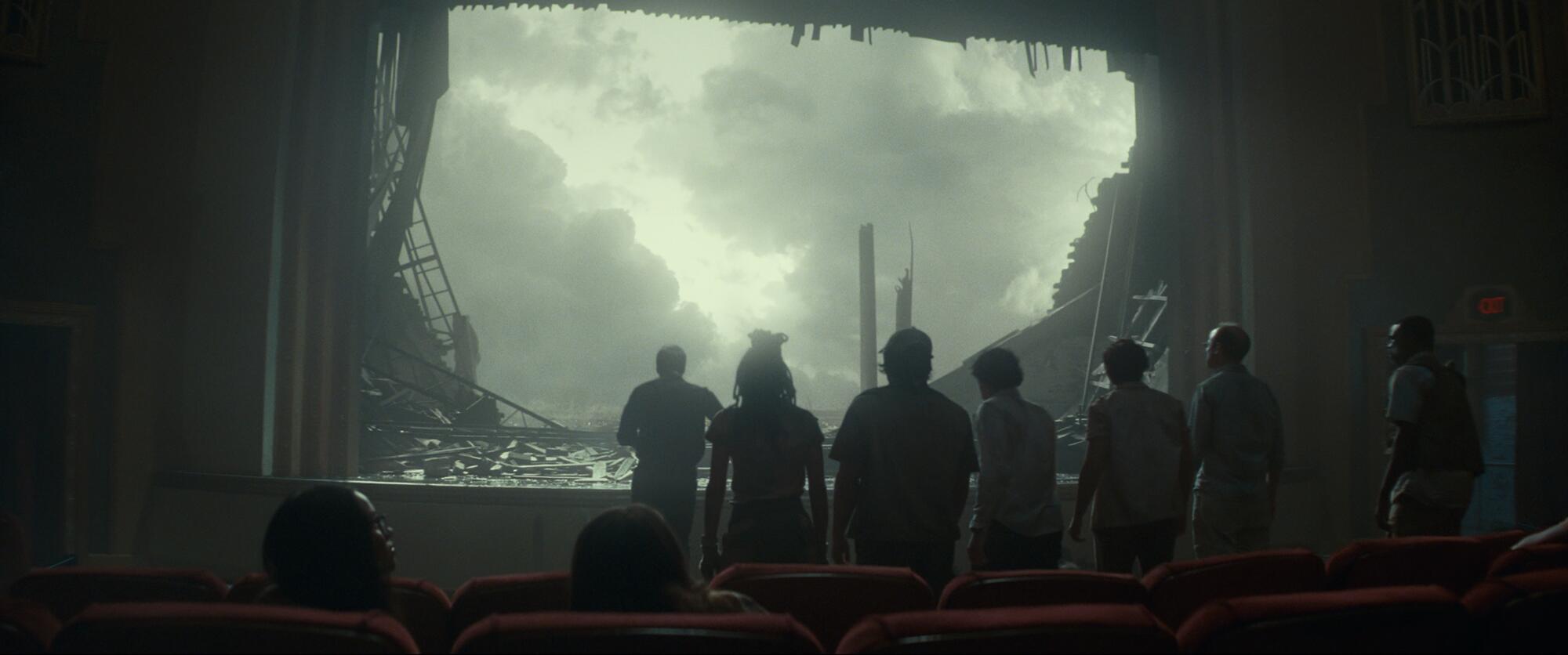 Survivors of a tornado gaze through the ruins of the screen.