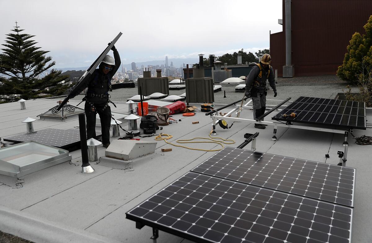 Workers install solar panels on the roof of a home on May 9, 2018 in San Francisco, California. 