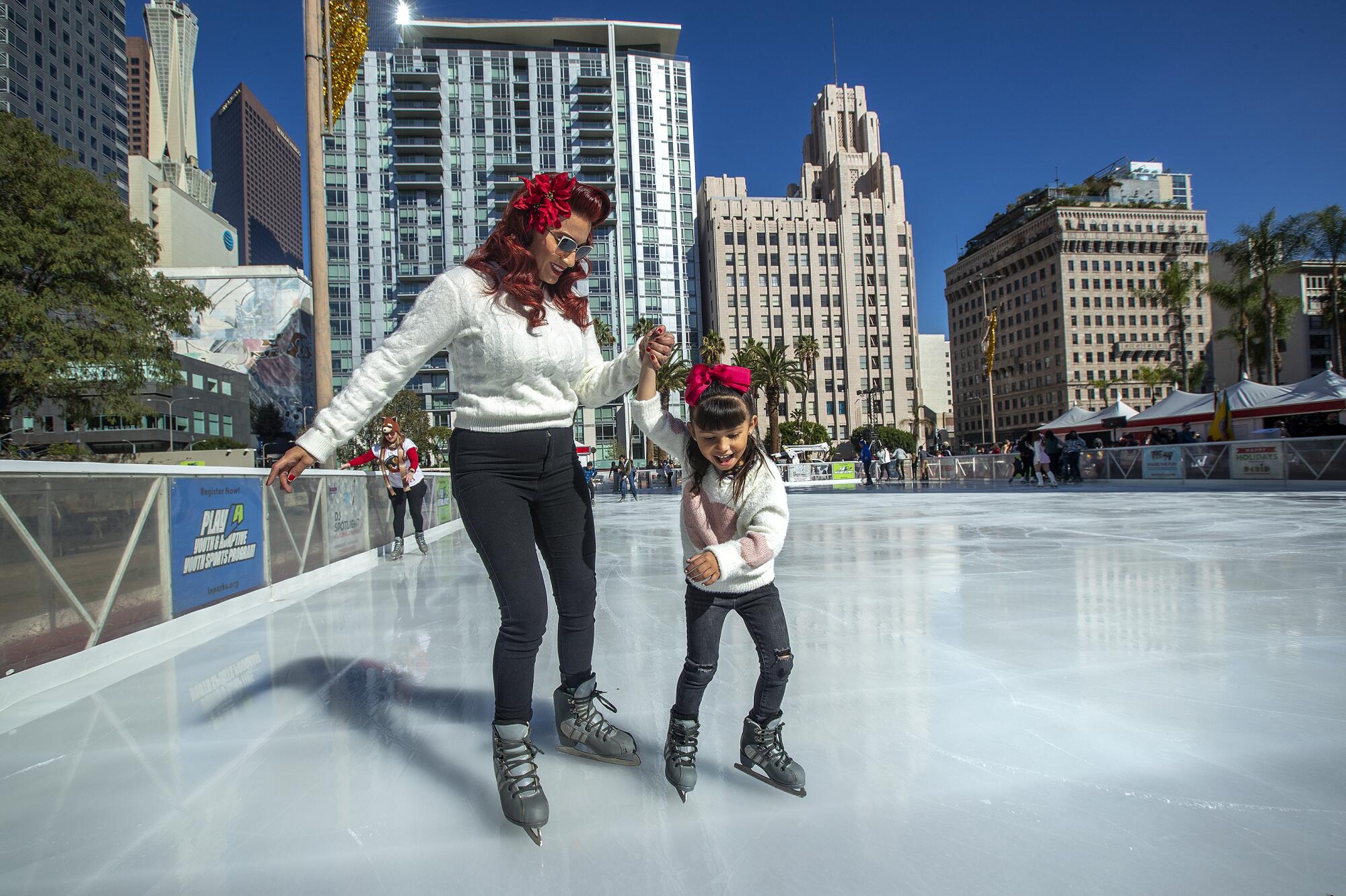 A woman and her young daughter enjoy ice skating together 