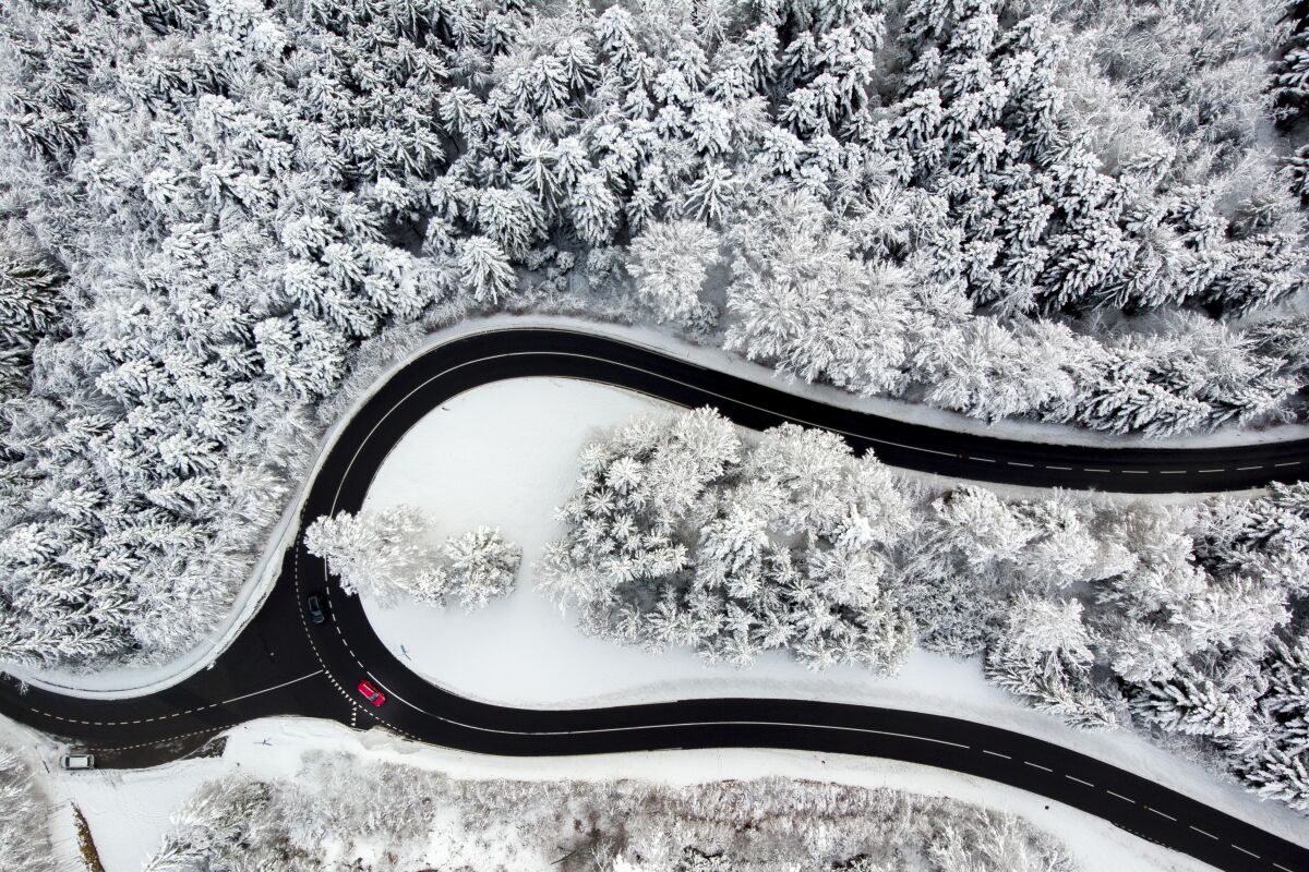 Cars drive on the road of the "Col du Mollendruz" among snow-covered trees in a forest after snowfall, in the Jura Mountains, in Mont-la-Ville, Switzerland, Sunday, Dec. 6, 2020. (Laurent Gillieron/Keystone via AP)