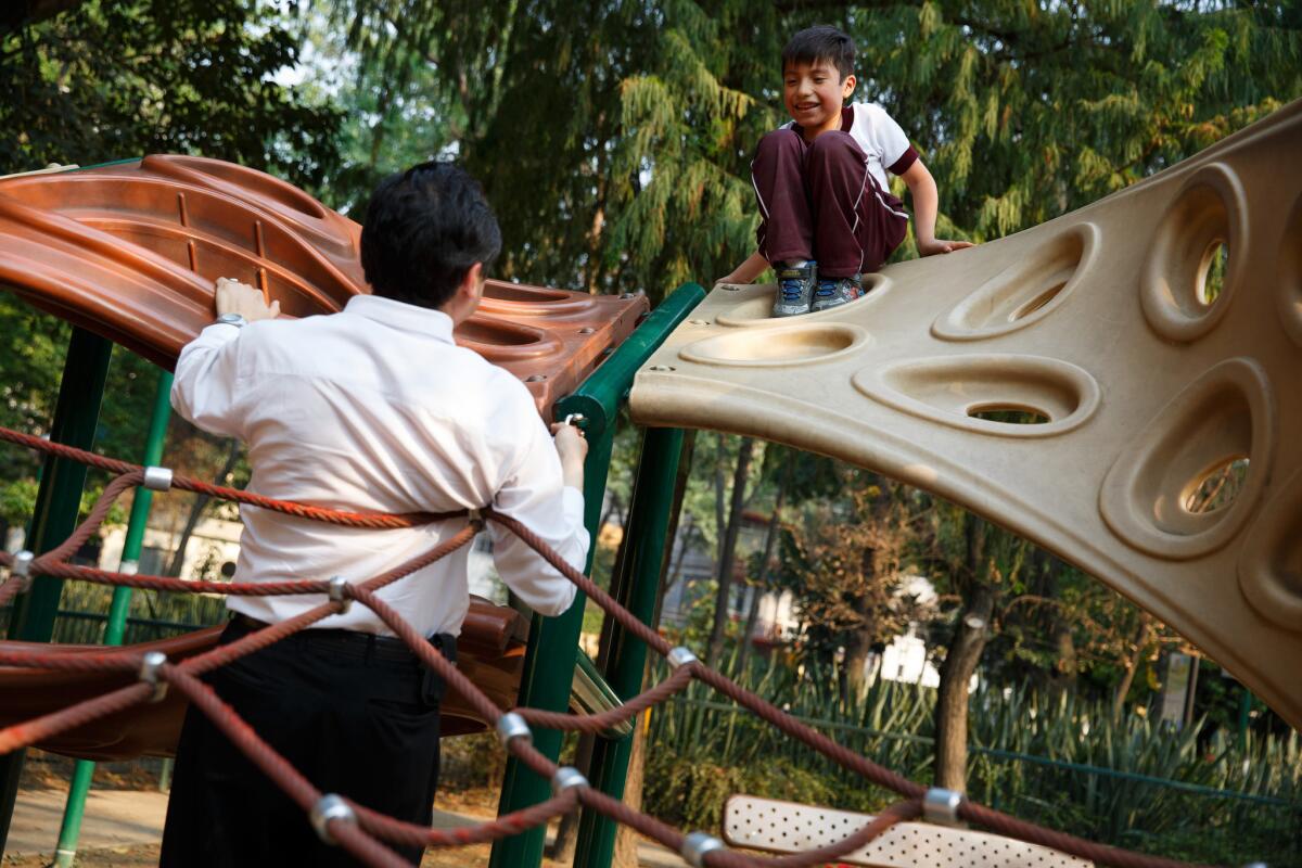 Andres Lopez plays with his son, Ernesto Lopez, 7, at the playground in Mexico City's Parque Espana.