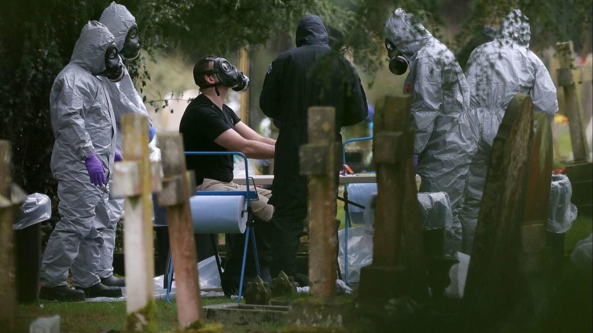 Members of the emergency services and police help colleague remove protective suit