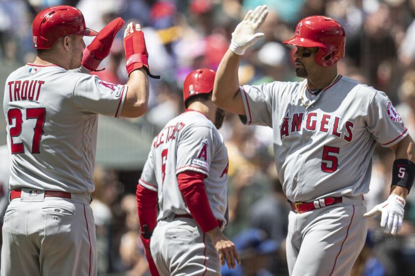 Los Angeles Angels' Albert Pujols, right, is congratulated by teammate Mike Trout after hitting a three-run home run off of Seattle Mariners starting pitcher Marco Gonzales that also scored Trout and David Fletcher during the second inning of a baseball game, Sunday, June 2, 2019, in Seattle. (AP Photo/Stephen Brashear)