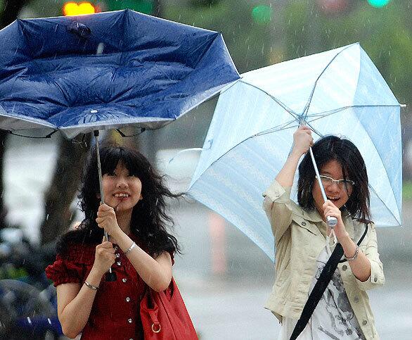 Two girls struggle with high winds as Taiwan deals with Typhoon Parma. The storm has lost strength but dumped heavy rain on the island.