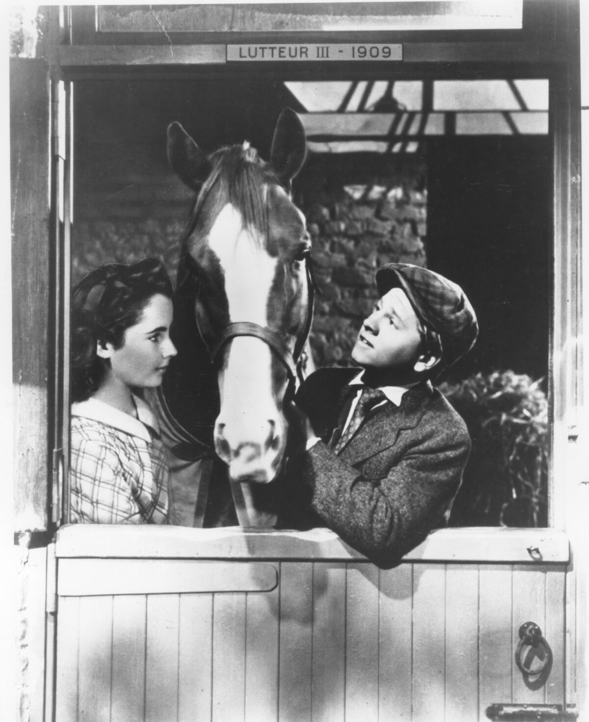  Elizabeth Taylor and Mickey Rooney look at a horse in a barn in “National Velvet" (1944)