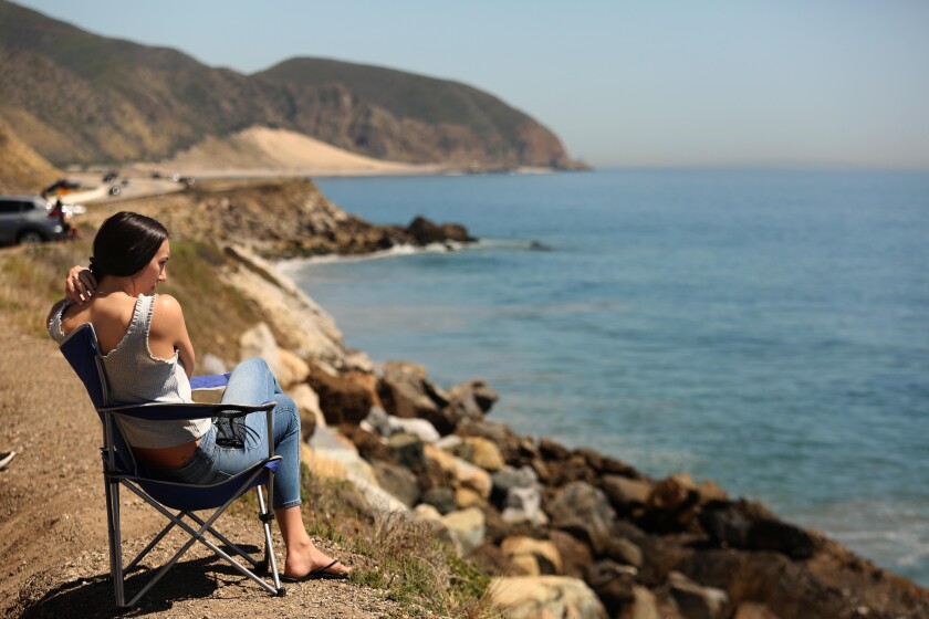Miriam Burciga, 27, enjoys a socially distant perch overlooking Point Mugu State Park along Pacific Coast Highway in Ventura County on April 15. Point Mugu State Park has been temporarily closed since April 7 in an effort to slow the spread of the coronavirus.