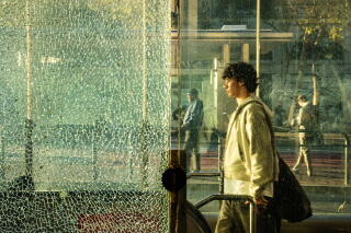 Passengers walk past a cracked window from the Civic Center BART station
