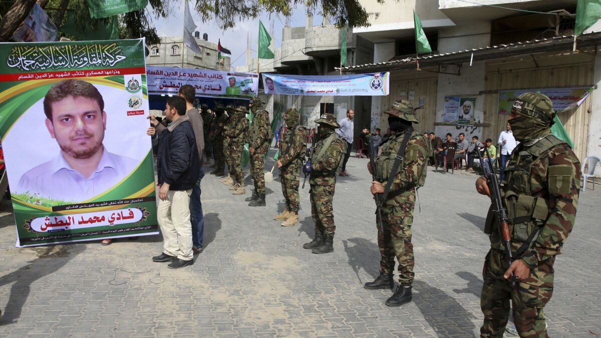 Relatives of Fadi Batsh display his photo as militants from the Izzidin al-Qassam Brigade, a military wing of Hamas, receive condolences at a house in Jebaliya, Gaza Strip. Batsh was killed in Malaysia on Saturday.