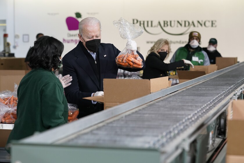 El presidente Joe Biden y la primera dama Jill Biden empacan zanahorias y manzanas