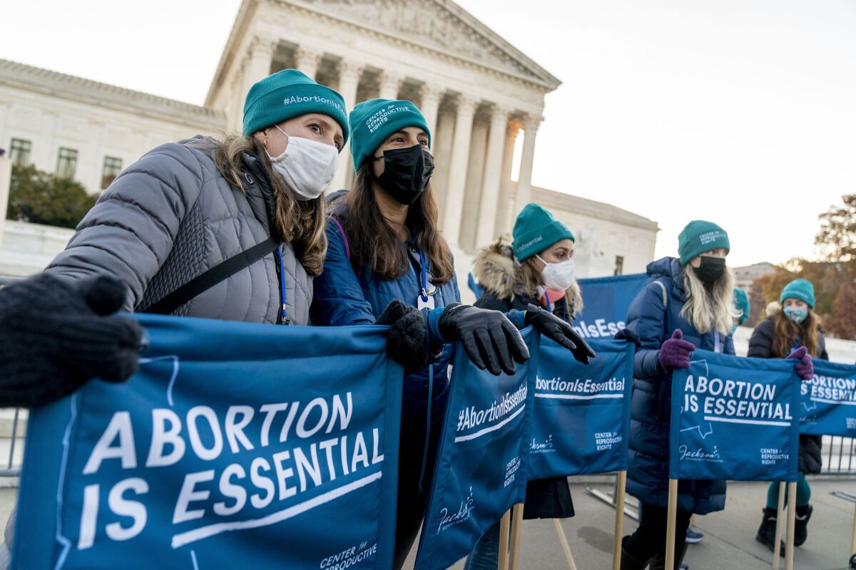 Abortion rights advocates hold signs that read "Abortion is Essential" as they demonstrate in front of the U.S. Supreme Court, Wednesday, Dec. 1, 2021, in Washington, as the court hears arguments in a case from Mississippi, where a 2018 law would ban abortions after 15 weeks of pregnancy, well before viability. (AP Photo/Andrew Harnik)