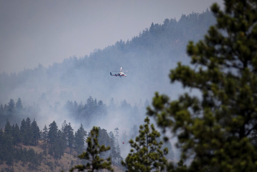 A helicopter pilot prepares to drop water on a wildfire burning in Lytton, B.C., on Friday, July 2, 2021. Officials on Friday hunted for any missing residents of a British Columbia town destroyed by wildfire as Canadian Prime Minister Justin Trudeau offered federal assistance. (Darryl Dyck/The Canadian Press via AP)