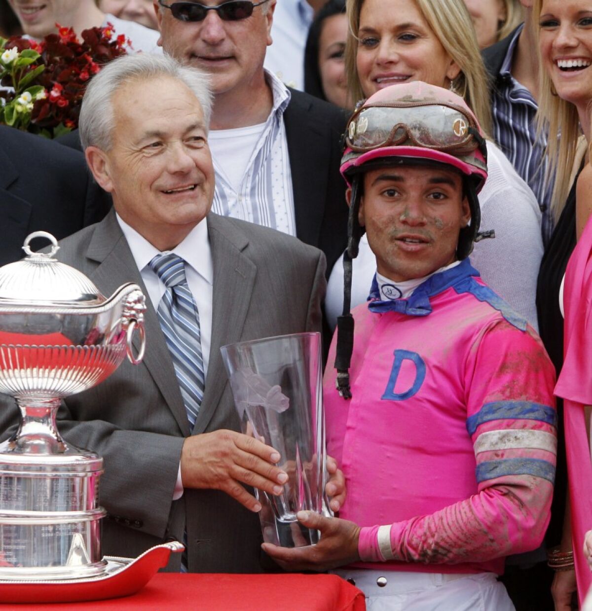 In this Aug. 21, 2010, file photo, Jockey Joel Rosario, right, and trainer Jerry Hollendorfer pose with trophies after Rosario rode Blind Luck to a win in the Alabama Stakes horse race at Saratoga Race Course in Saratoga Springs, N.Y.