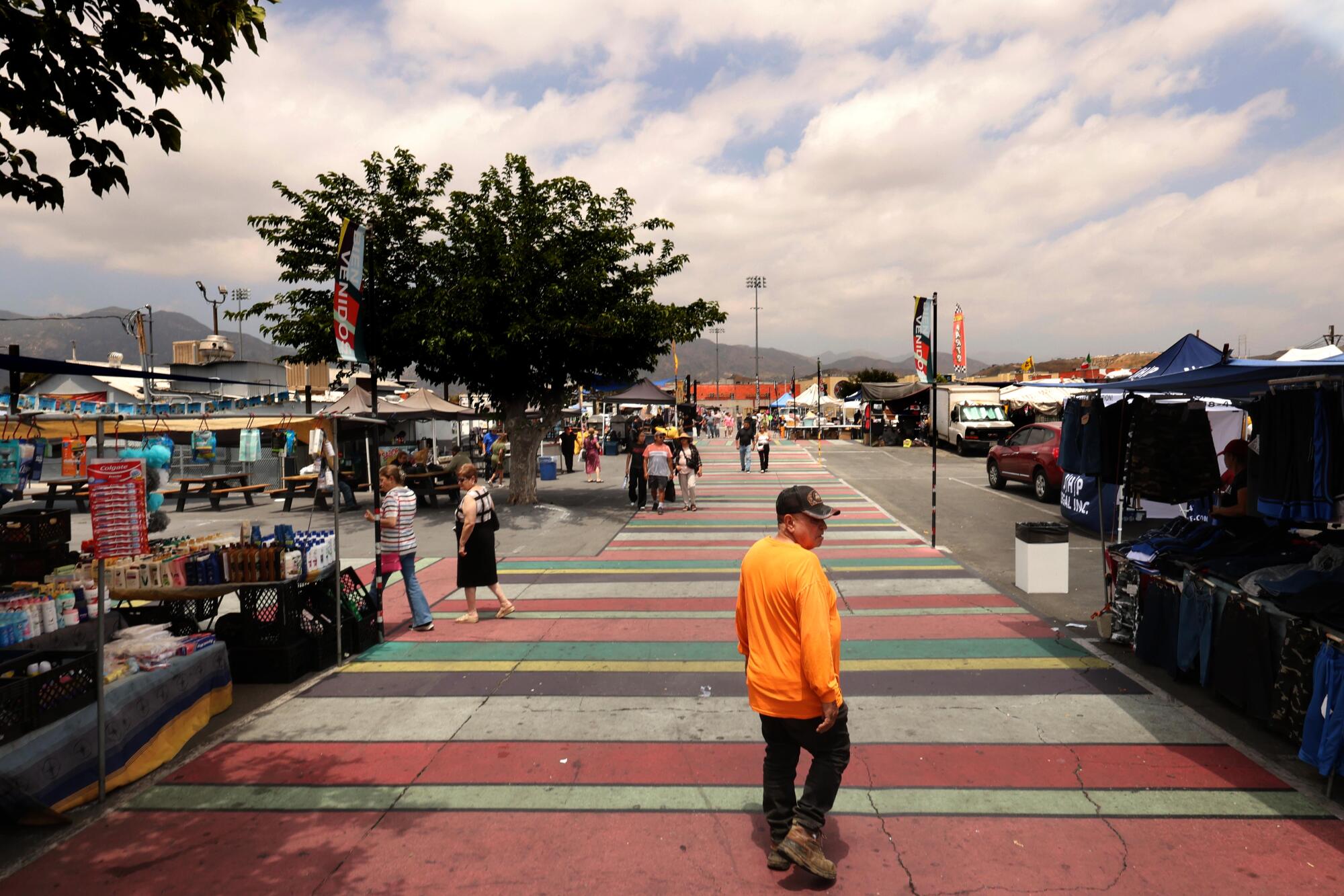 a man in an orange shirt walks through the San Fernando Swap Meet