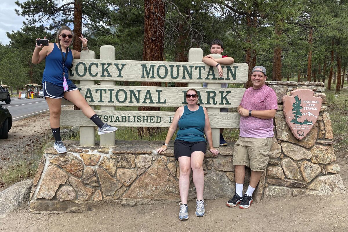 In this July 26, 2020, family photo provided by Erin Marshall, Julia Silver, from left, Shannon Silver, seated, John Silver Jr., and John Silver Sr., from Connecticut, pose for a photo during their vacation at Rocky Mountain National Park, in Colorado. As states around the country require visitors from areas with high rates of coronavirus infections to quarantine upon arrival, children taking end-of-summer vacations to hot spots are facing the possibility of being forced to skip the start of in-person learning at their schools. The Silver family went to Colorado instead of to Ohio because Connecticut for a time required travelers to Ohio to quarantine upon their return. (Courtesy Erin Marshall via AP)
