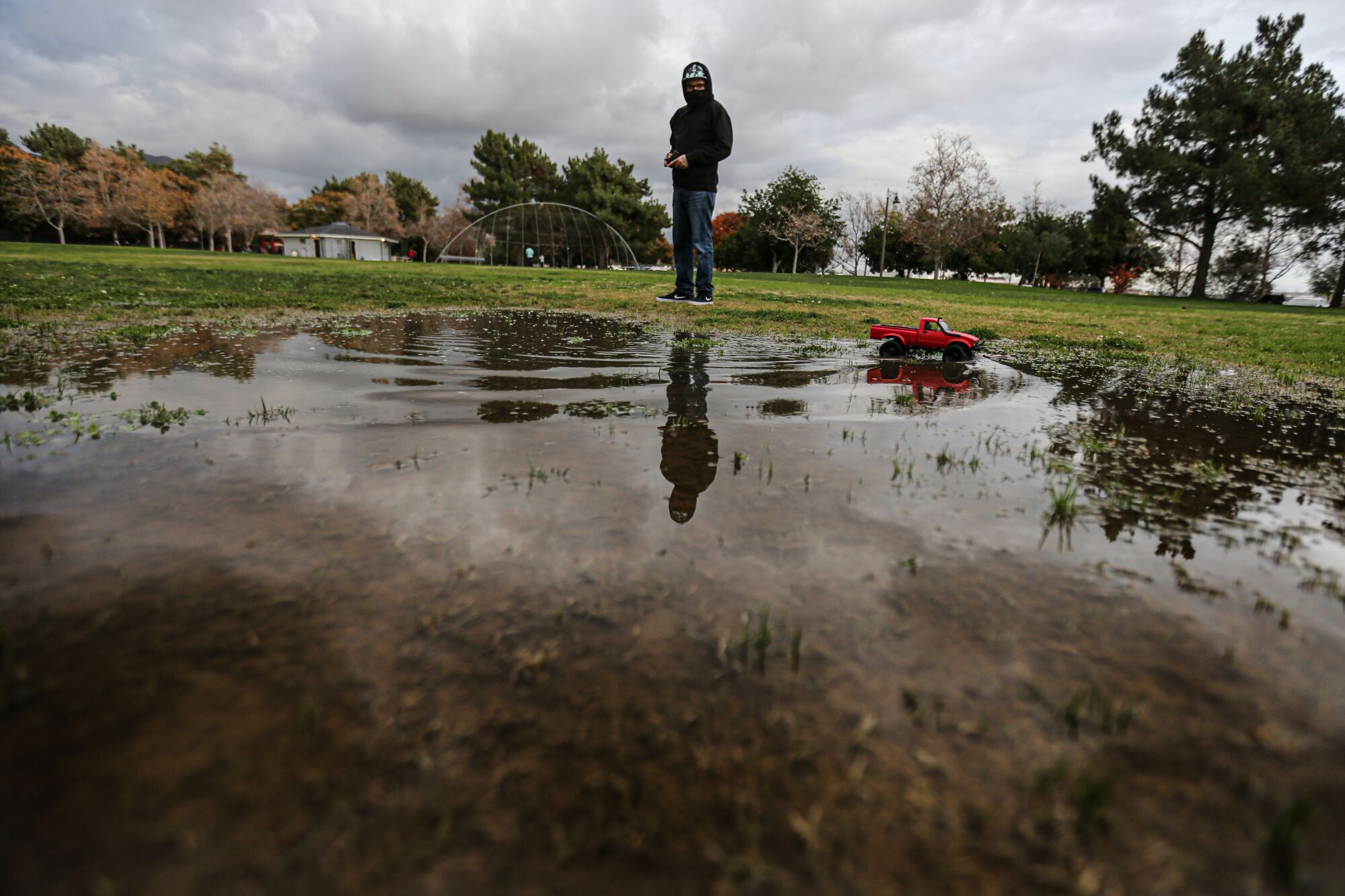 Gerry Baltierra directs a radio-controlled car through a puddle at Encanto Park. 