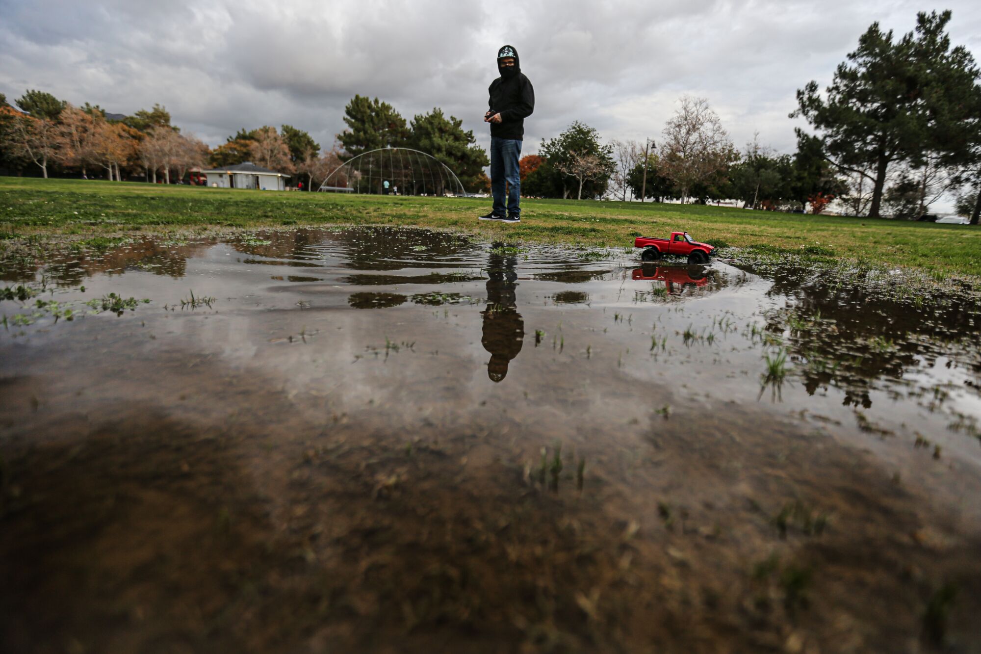 Gerry Baltierra directs a radio-controlled car through a puddle at Encanto Park.