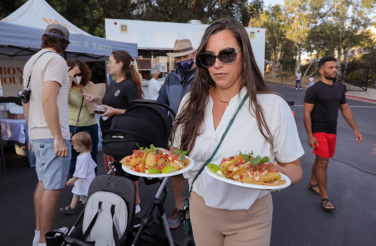 Dominique Delgado of Fallbrook carries two plates of three vegan fish tacos each.