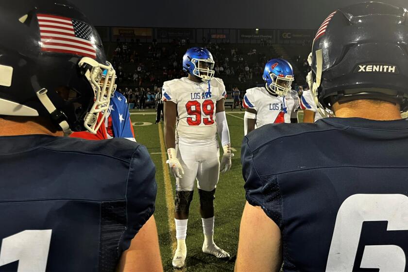 T.A. Cunningham (99) joins the Los Alamitos captains for the coin flip before a game against Newport Harbor.