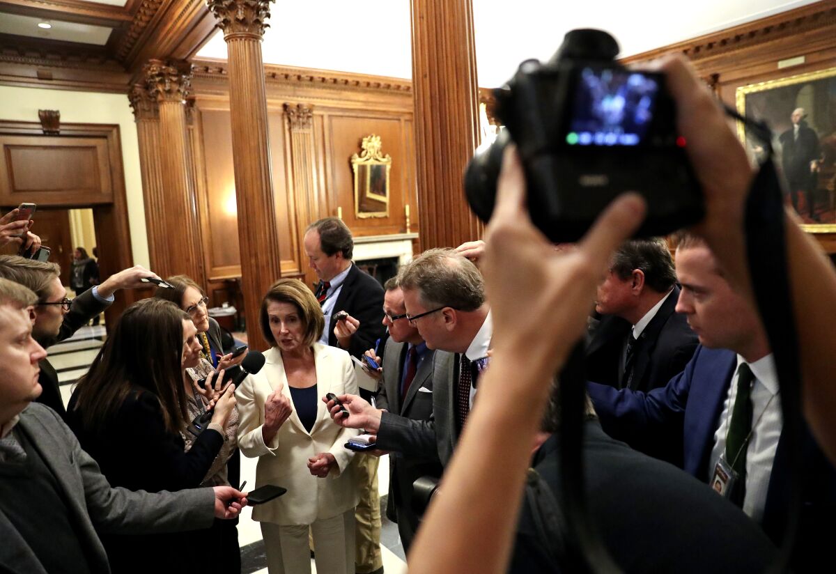 Rep. Nancy Pelosi speaks at the center of a crowd of reporters