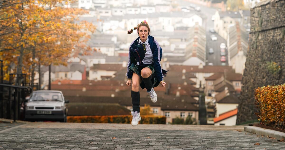 A schoolgirl in her uniform dances in the street in autumn