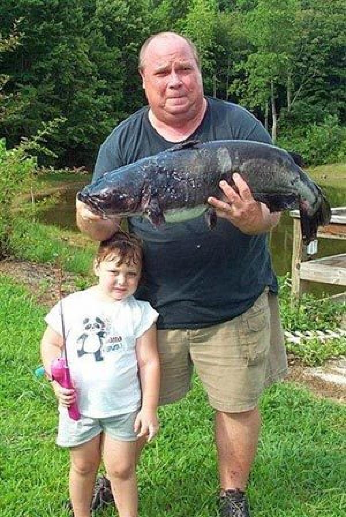 In this undated photo released by the N. C. Wildlife Resources Commission, David Hayes holds his state record-breaking channel catfish while his three-year-old granddaughter Alyssa holds the Barbie rod and reel that Hayes used to reel in the 21-pound, 1 ounce fish in Elkin, N.C.