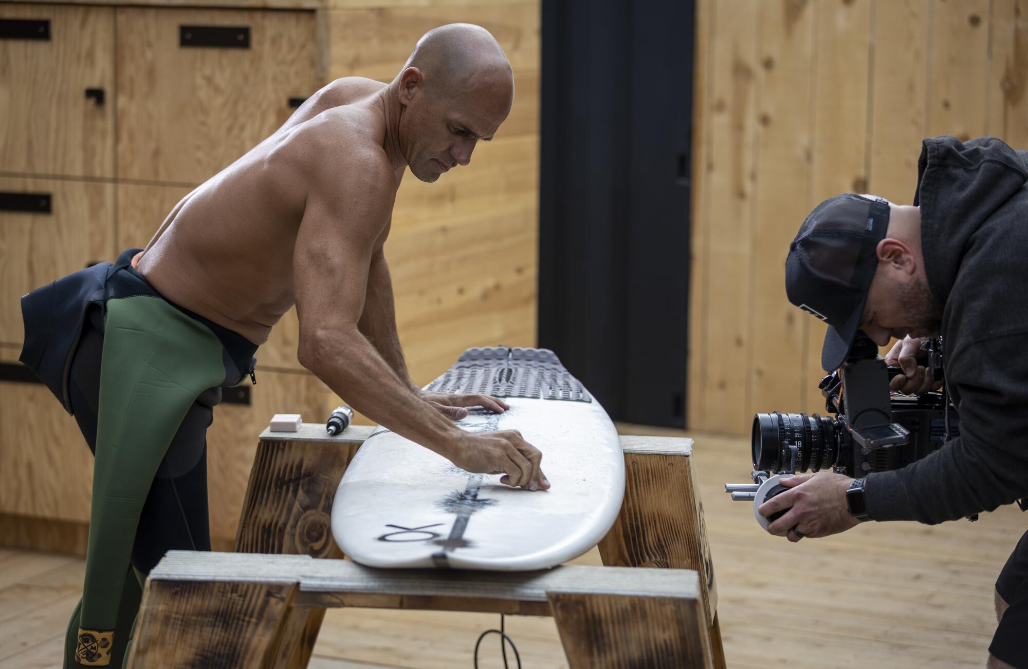 Kelly Slater waxes his board on the set of “The Ultimate Surfer."