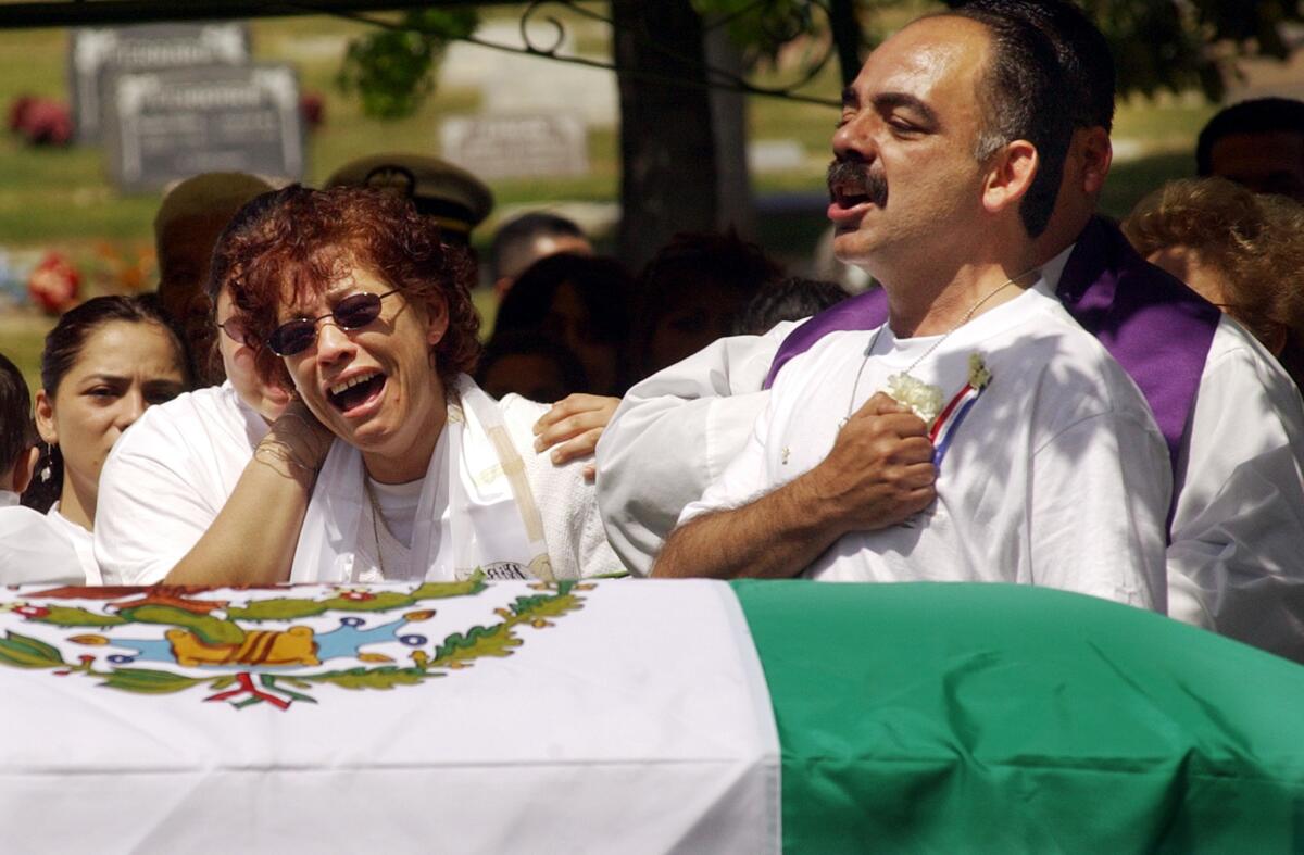 Fernando Suarez del Solar sings the Mexican national anthem as his wife Rosa weeps at their son Marine Lance Cpl. Jesus Suarez del Solar's funeral on April 11, 2003, at St. Mary's Catholic Church in Escondido.