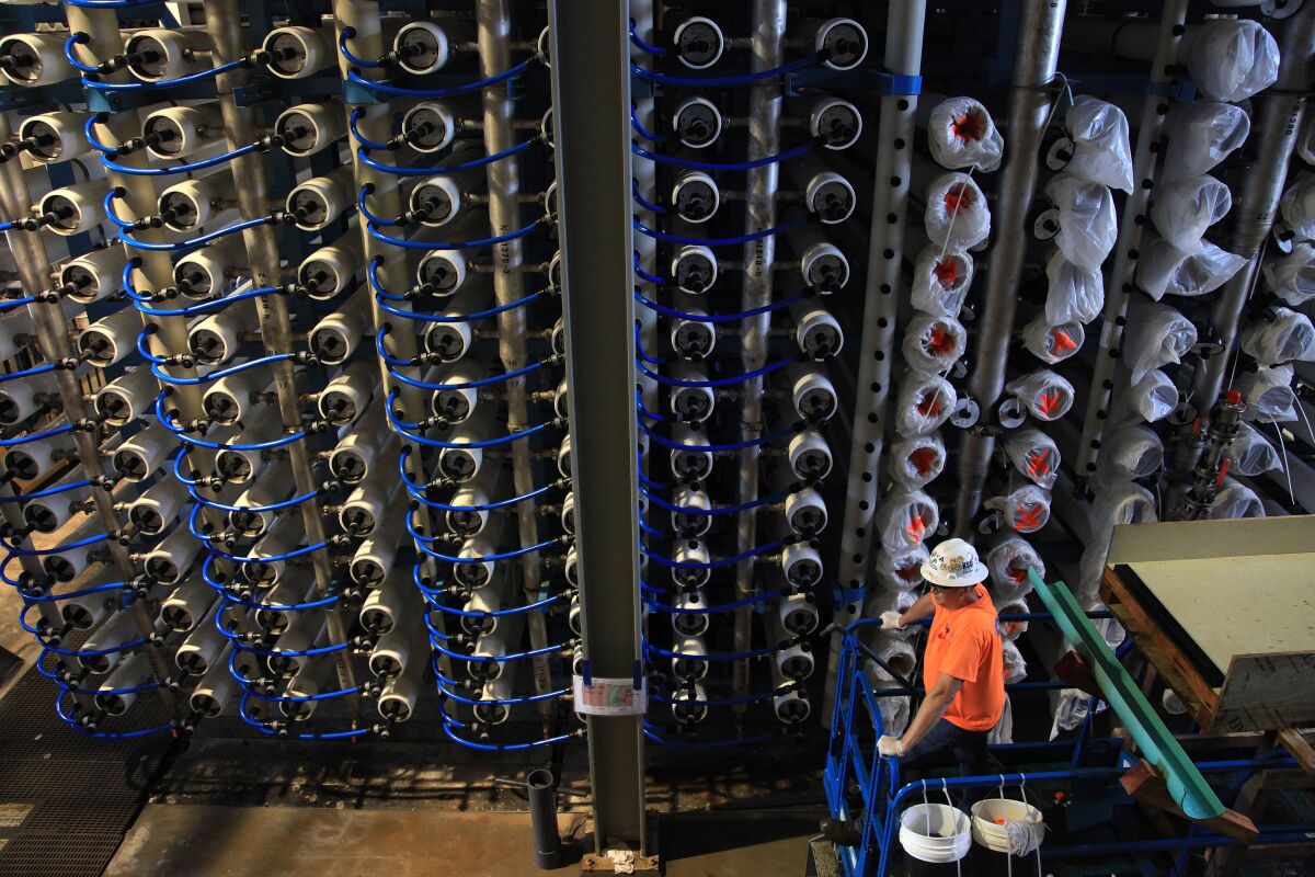 A man looks at rows of reverse osmosis membranes at the Poseidon desalination plant in Carlsbad. 