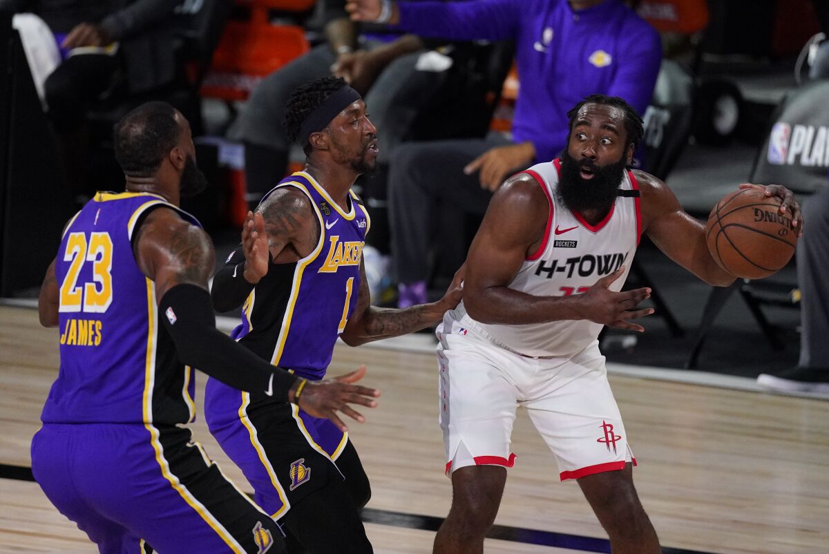 Rockets guard James Harden draws the double-team defense of Lakers guard Kentavious Caldwell-Pope and forward LeBron James.