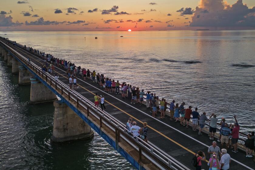 In this aerial photo provided by the Florida Keys News Bureau, attendees watch and toast the sunset at a Florida Keys bicentennial celebration, Friday, May 19, 2023, on the restored Old Seven Mile Bridge in Marathon, Fla. The sunset gathering was among a series of Keys events being staged to mark the 200th anniversary, on July 3, of the Florida Territorial Legislature's 1823 founding of Monroe County, containing the entire island chain. The old bridge was originally part of Henry Flagler's Florida Keys Over-Sea Railroad completed in 1912, and is now closed to vehicles but open to pedestrians and bicycles. (Andy Newman/Florida Keys News Bureau via AP)
