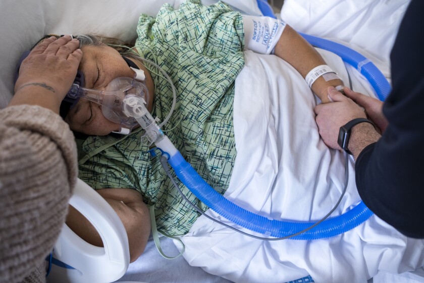 Chaplain Kevin Deegan, right, prays with Marylou Samora at Providence Holy Cross Medical Center.