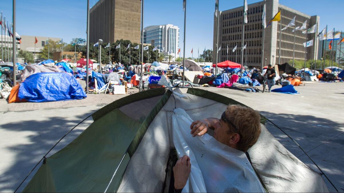 A homeless man sets up his tent at a homeless encampment at the Santa Ana Civic Center. The Orange County Needle Exchange Program operated in the center before its permit application was denied by the city.